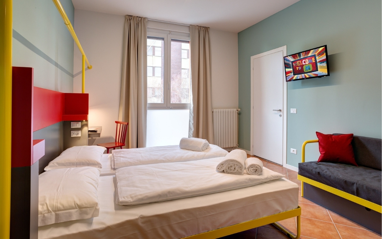 Bedroom with 2 single beds, a couch, a small TV and a large window