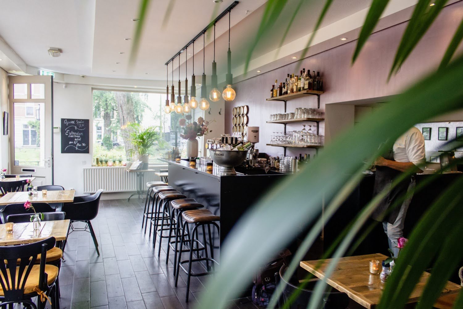 A long shot of a cafe space, bright room, no people, just coffee tables