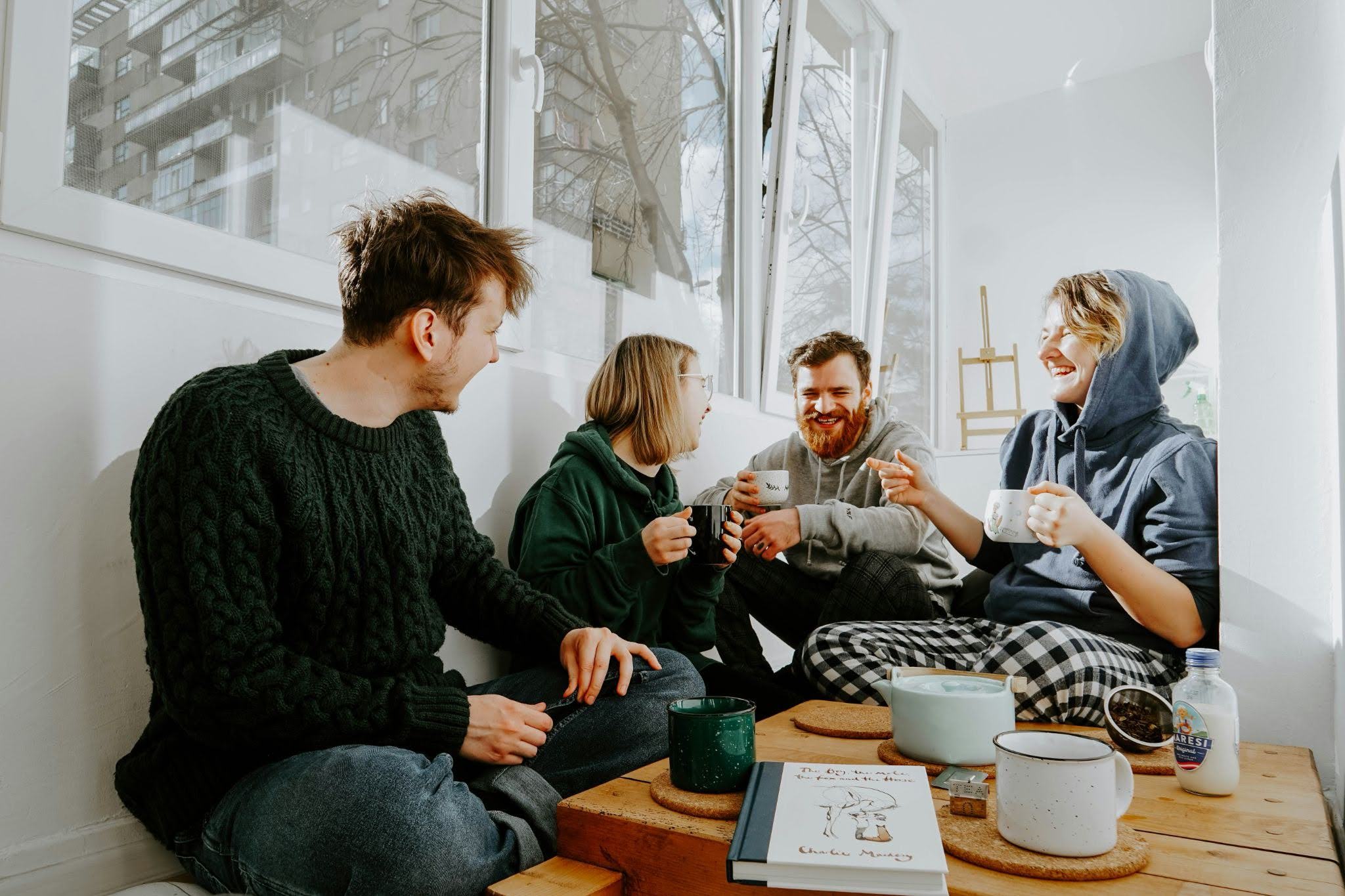 Starting your day with laughter and friends is pure happiness: a group of four people sitting together and talking over a table.