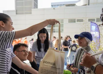 A youth worker is handing a tote bag to a participant of EGM Split 2026