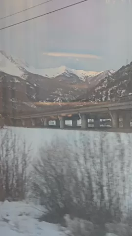 Cinematic snow covered mountains and a bridge seen from a moving train.