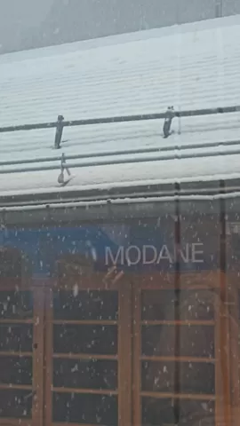 A snowy view of the Modane station sign seen through a train window.