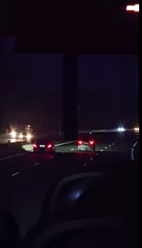 A night view from a vehicle of car tail lights on a dark highway.