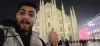 A nighttime selfie of me giving a thumbs up in front of the illuminated Milan Duomo cathedral.