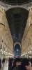 A low angle photo looking up at the high, arched glass ceiling and ornate facades of an architectural gallery in Milan at night.