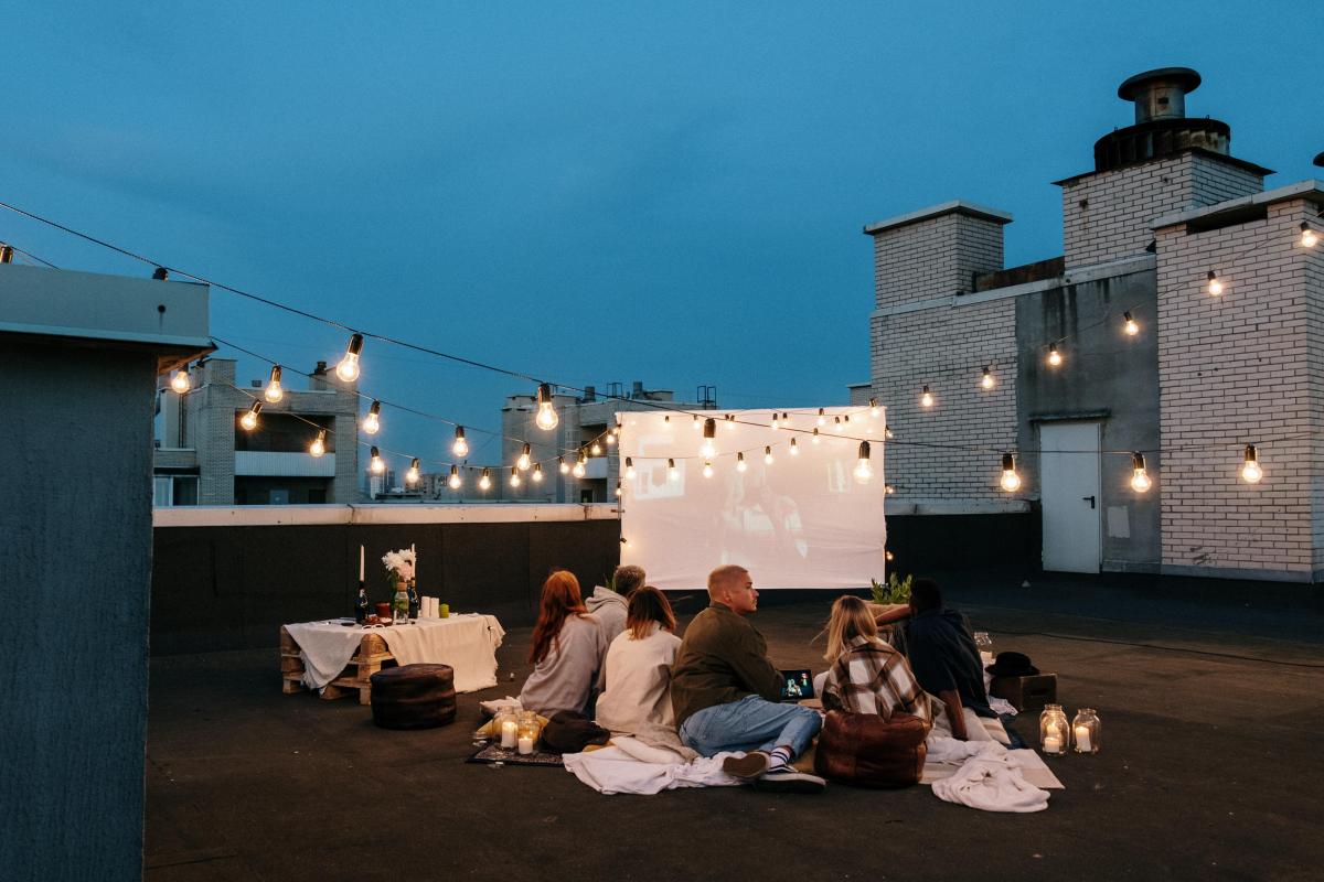 People sit on rooftop with lights at evening