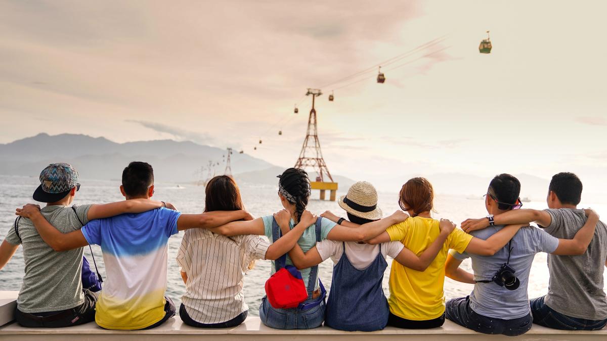 People holding shoulders sitting on wall