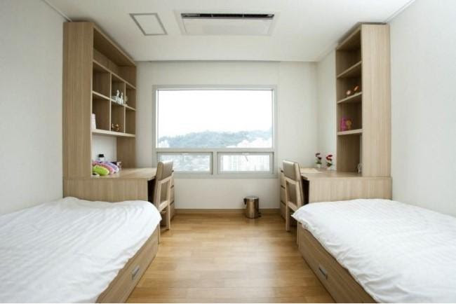 Two beds and desks aligned on each side of a shared room