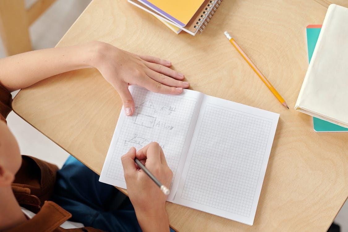 someone doing math on a notebook, view from top