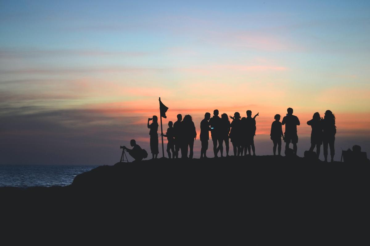 silhouette photography of people gathered together on cliff