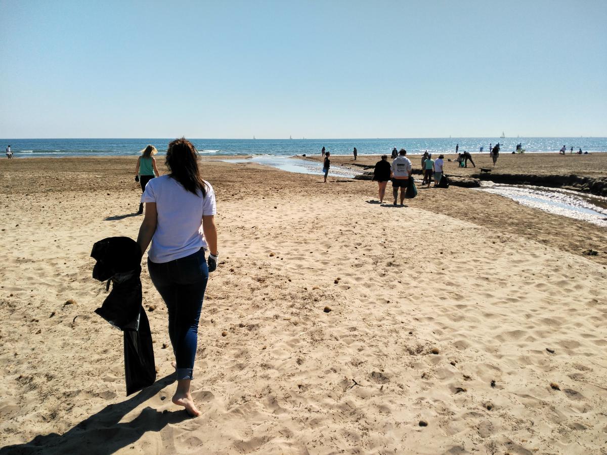 someone with a trash bag on the beach