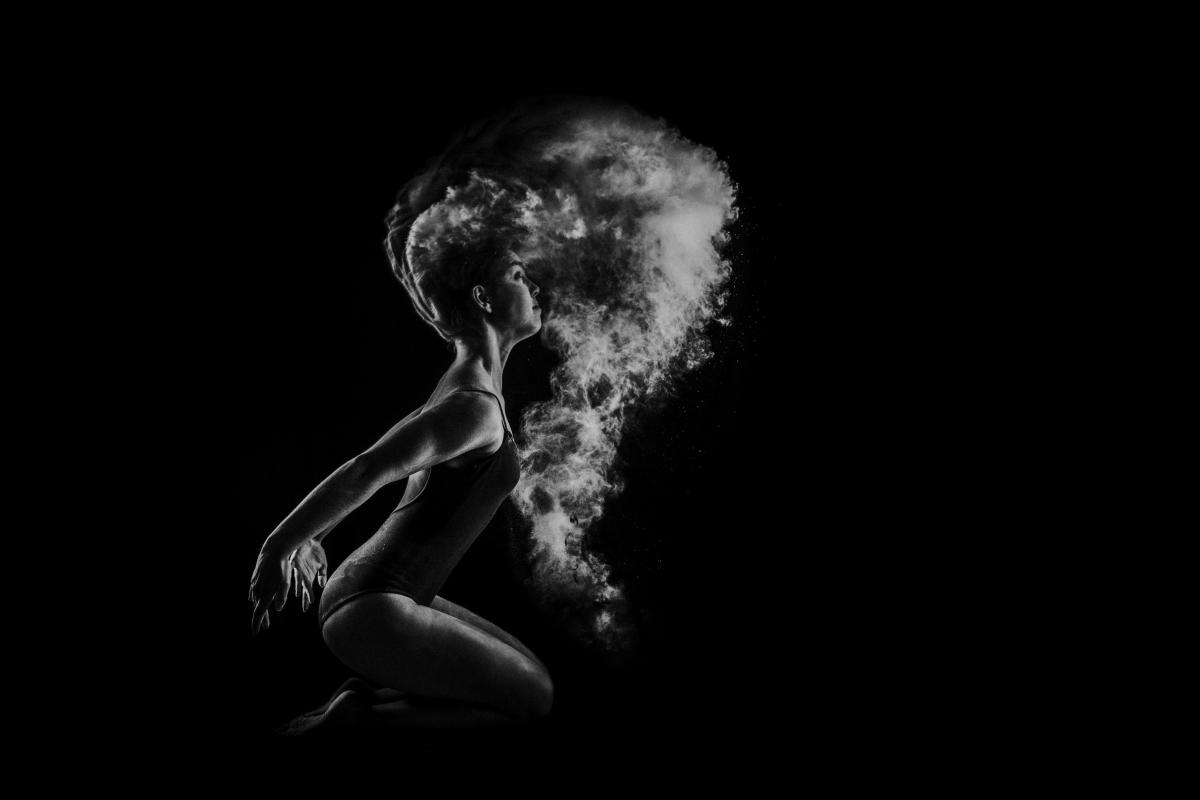someone in a gymnastic pose with smoke behind, black and white