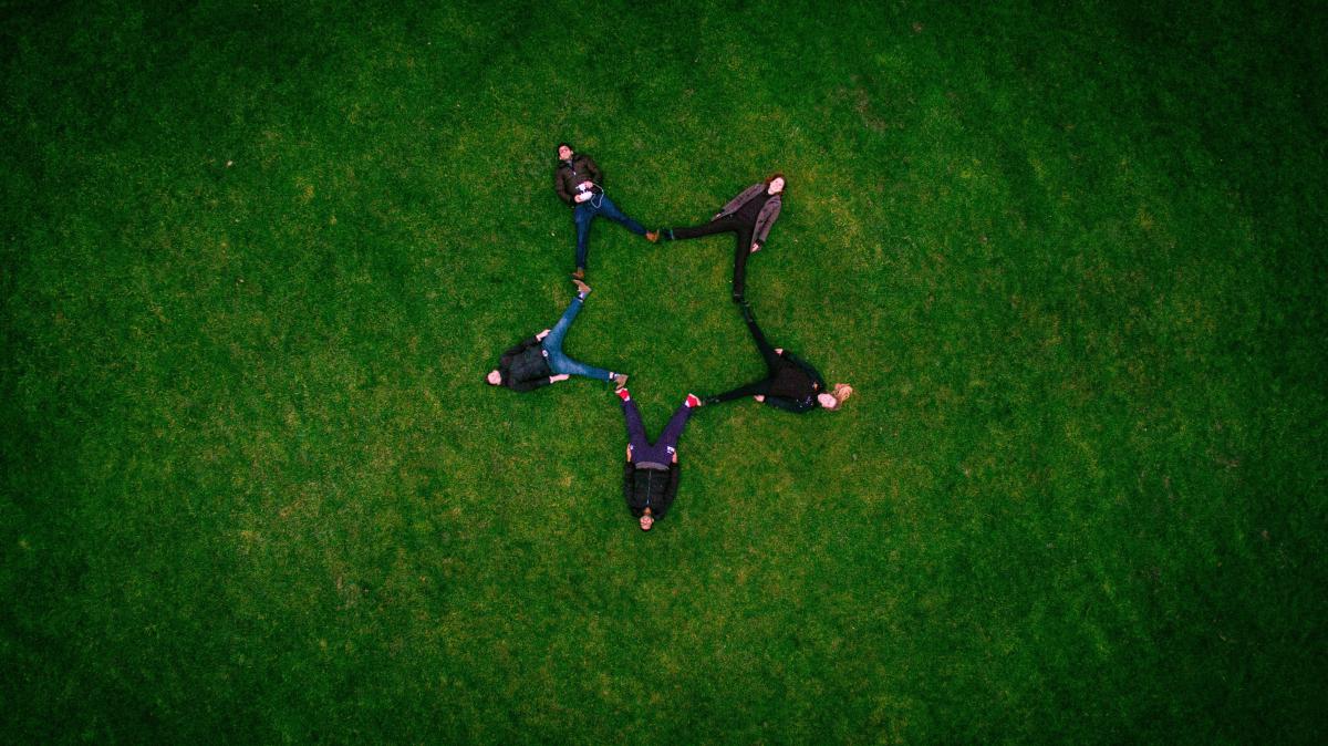 people laying down on grass, in star shaped form