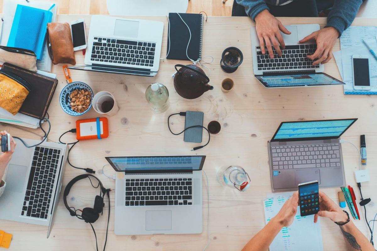 people working on table, from above with laptops, phones, notes