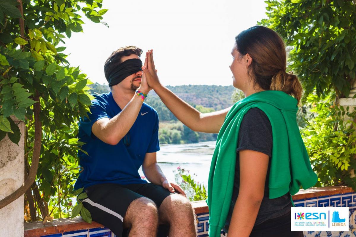 people touching hands, one is blind folded