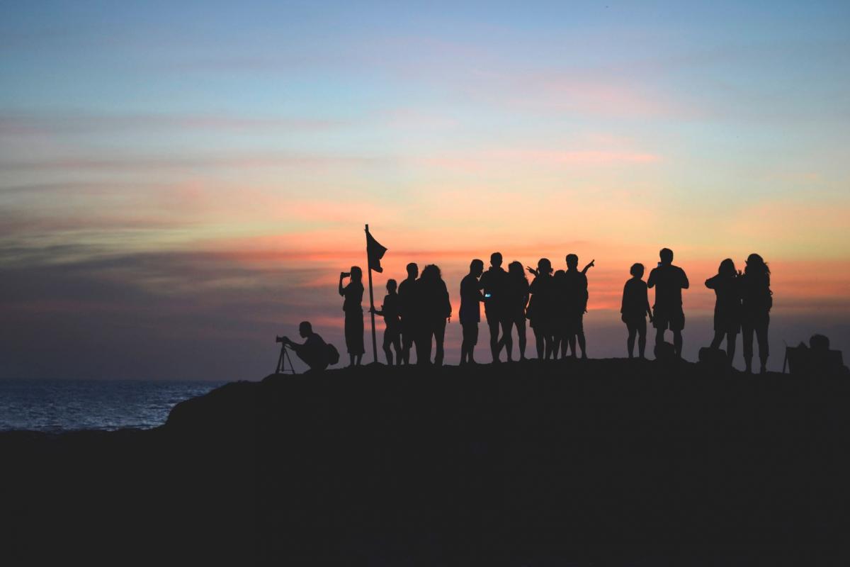 people on hill at sunset