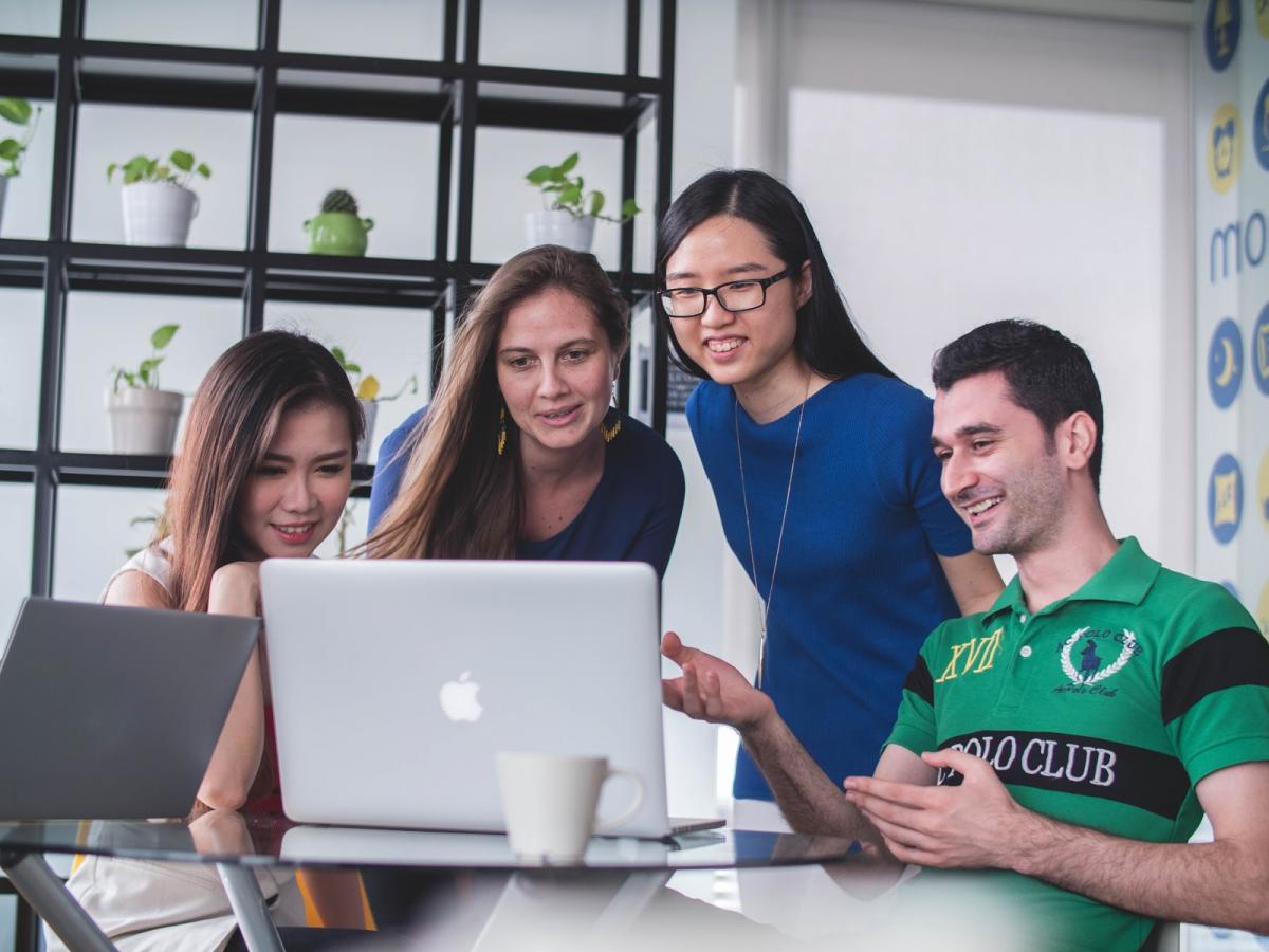 four people in front of laptop discussing