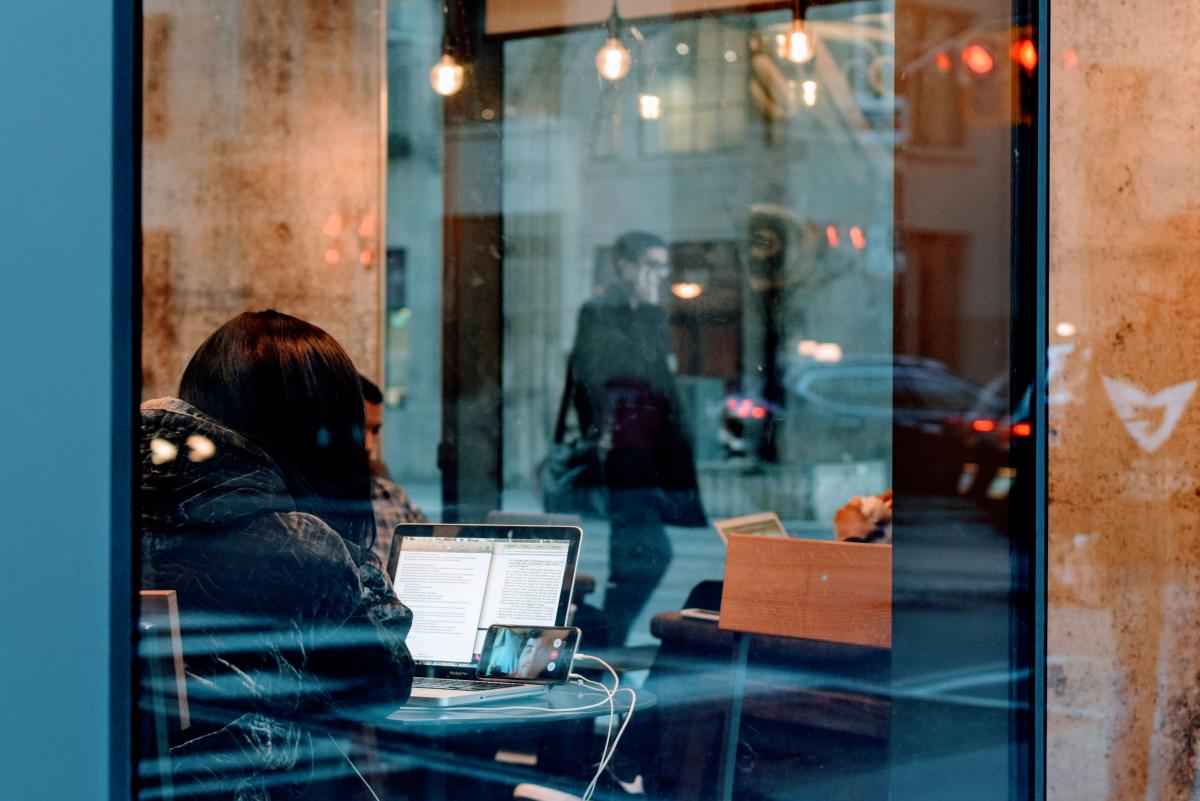 woman on laptop in cafe through window
