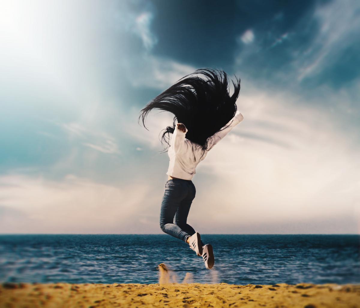 woman jumping in the air on beach