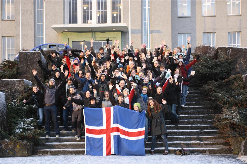 friends group picture with flag in front of entrance of building