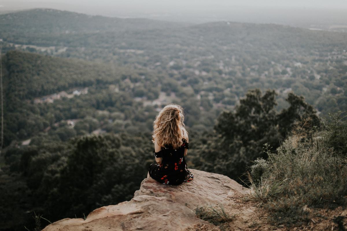 woman sitting looking at forest below