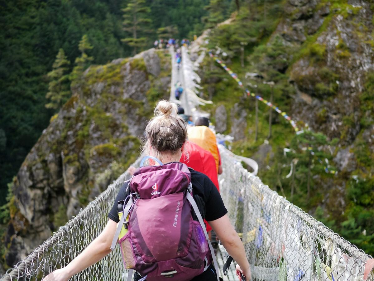 people with backpack crossing a bridge