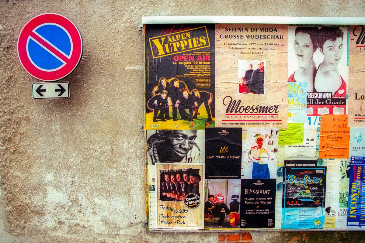 posters on street wall next to road sign