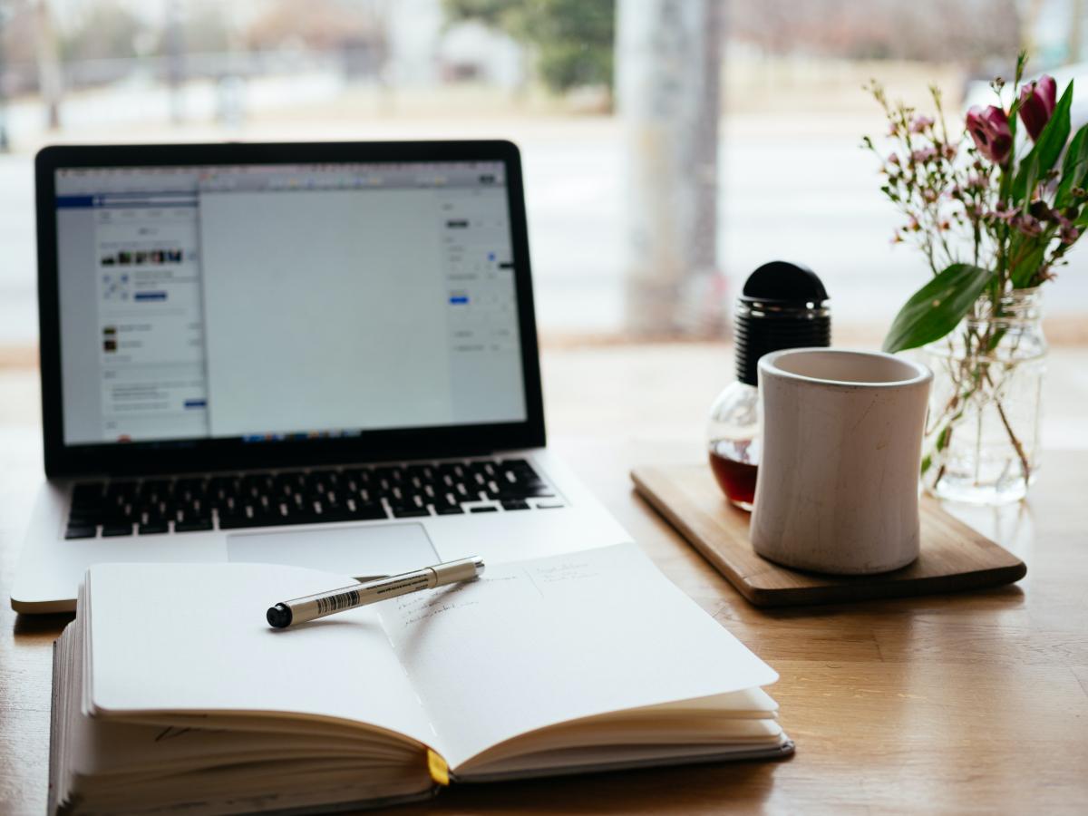 laptop, open notebook and mug on desk