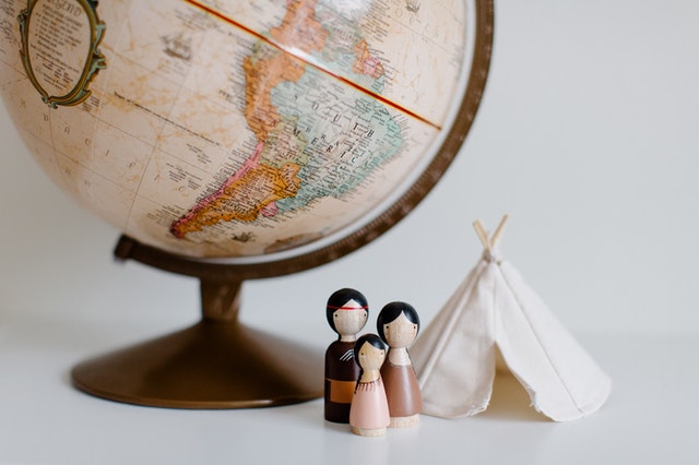 Retro globe with handmade toys against gray background