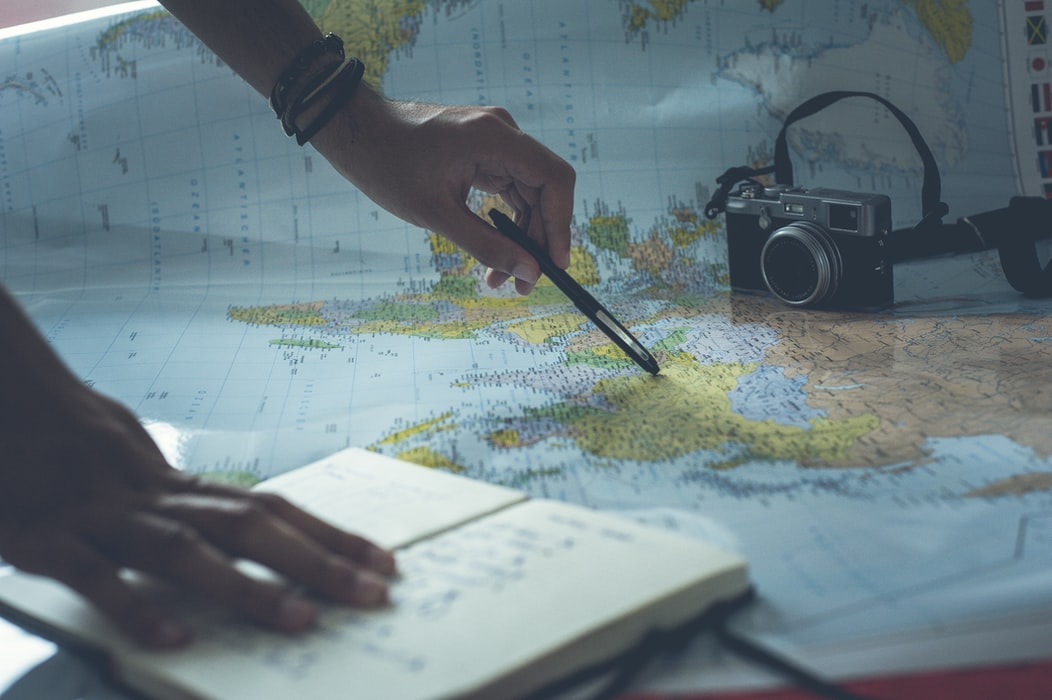 pointing a pen on map with notebook and camera