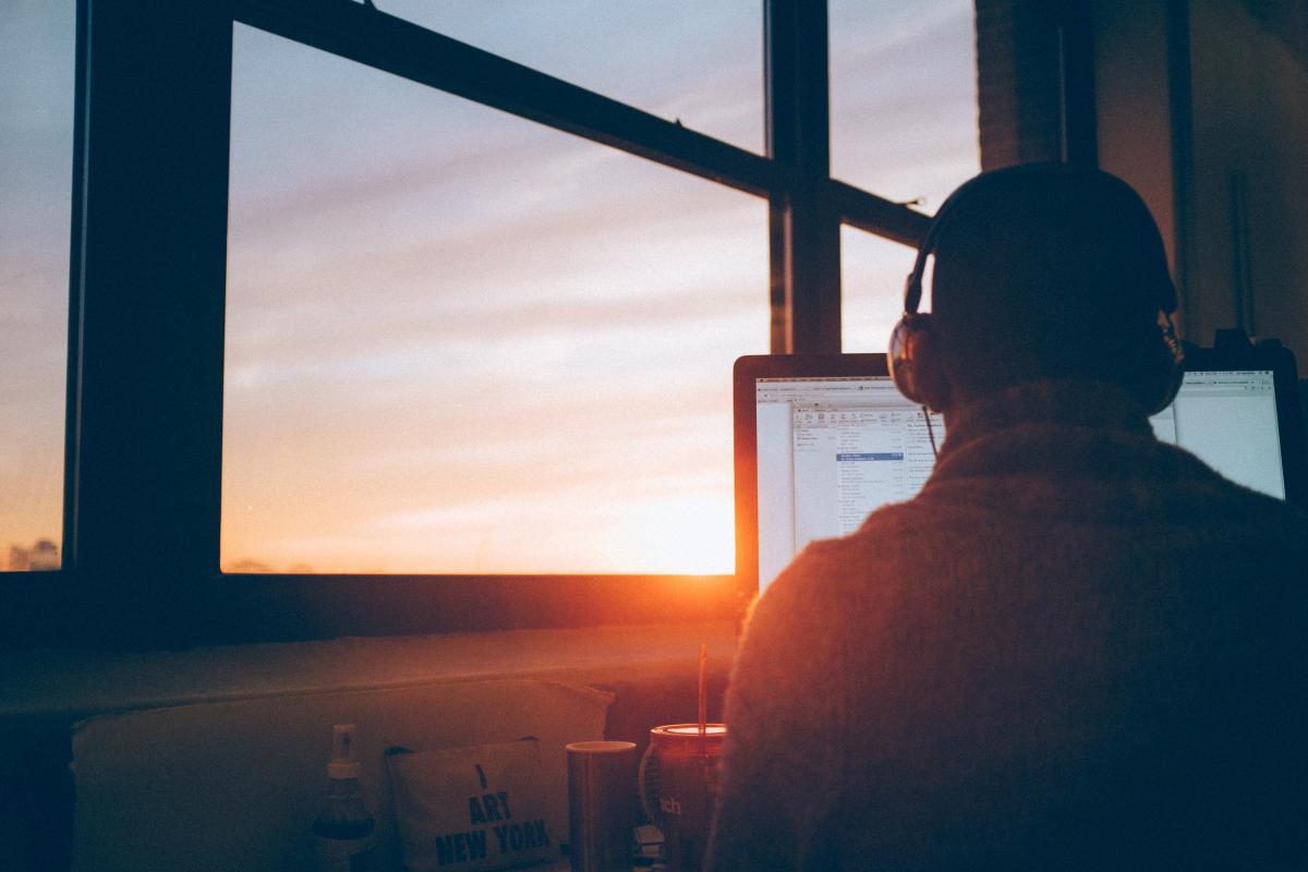 man next to window with laptop and headphones