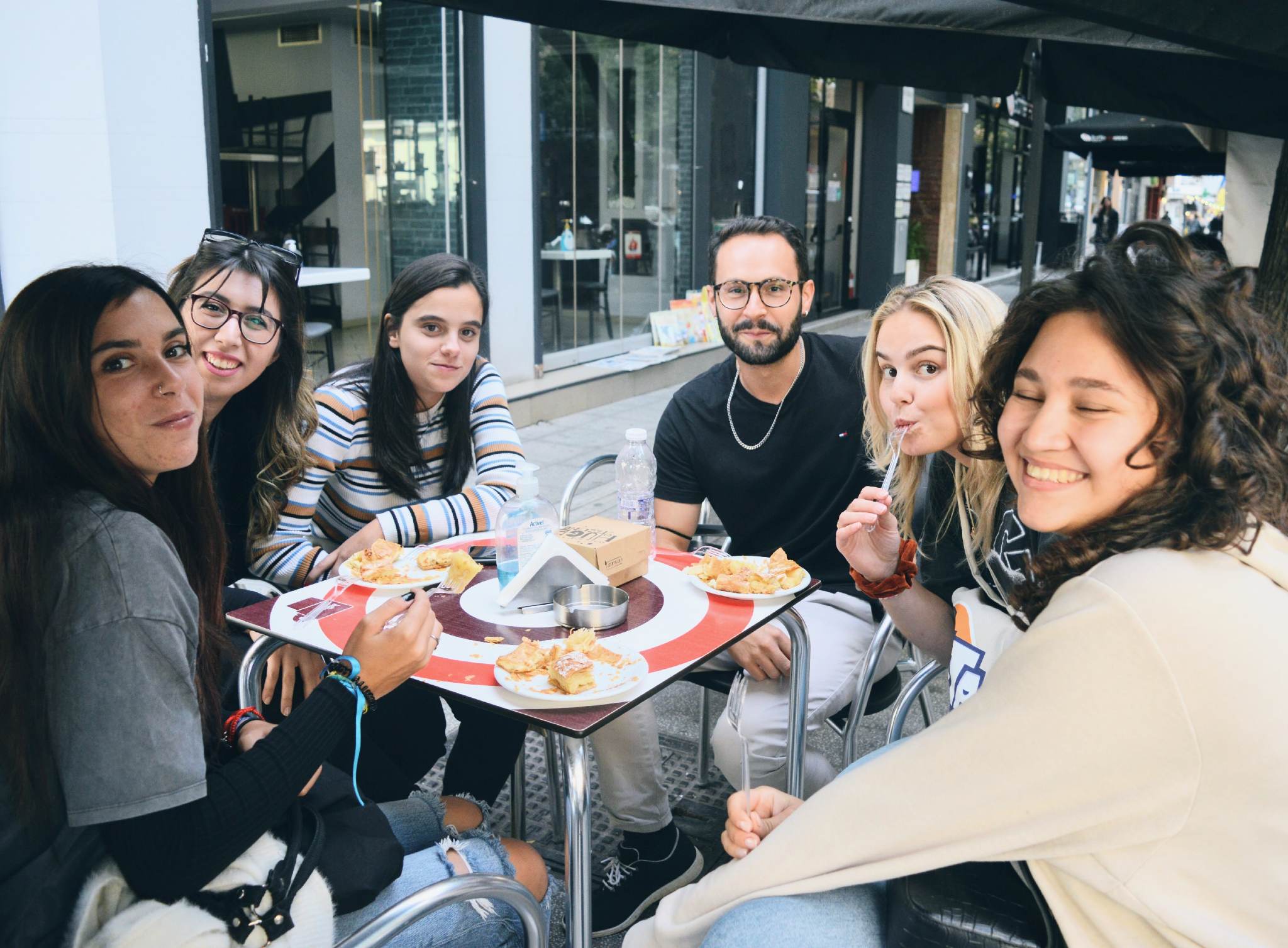 A group of peopple sitting around the table, eating and smiling