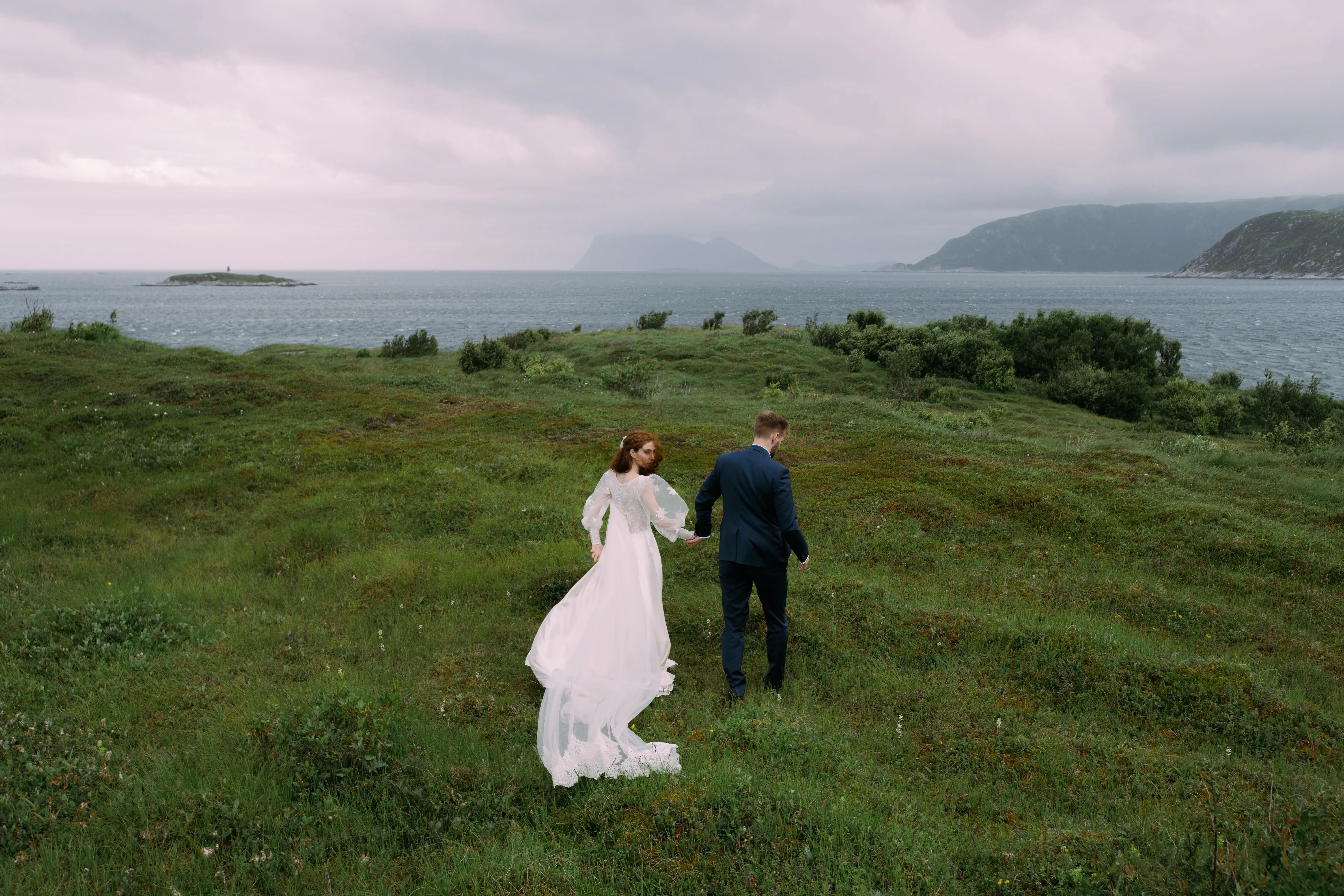 Barbara and Peder on their wedding day, walking through a meadow