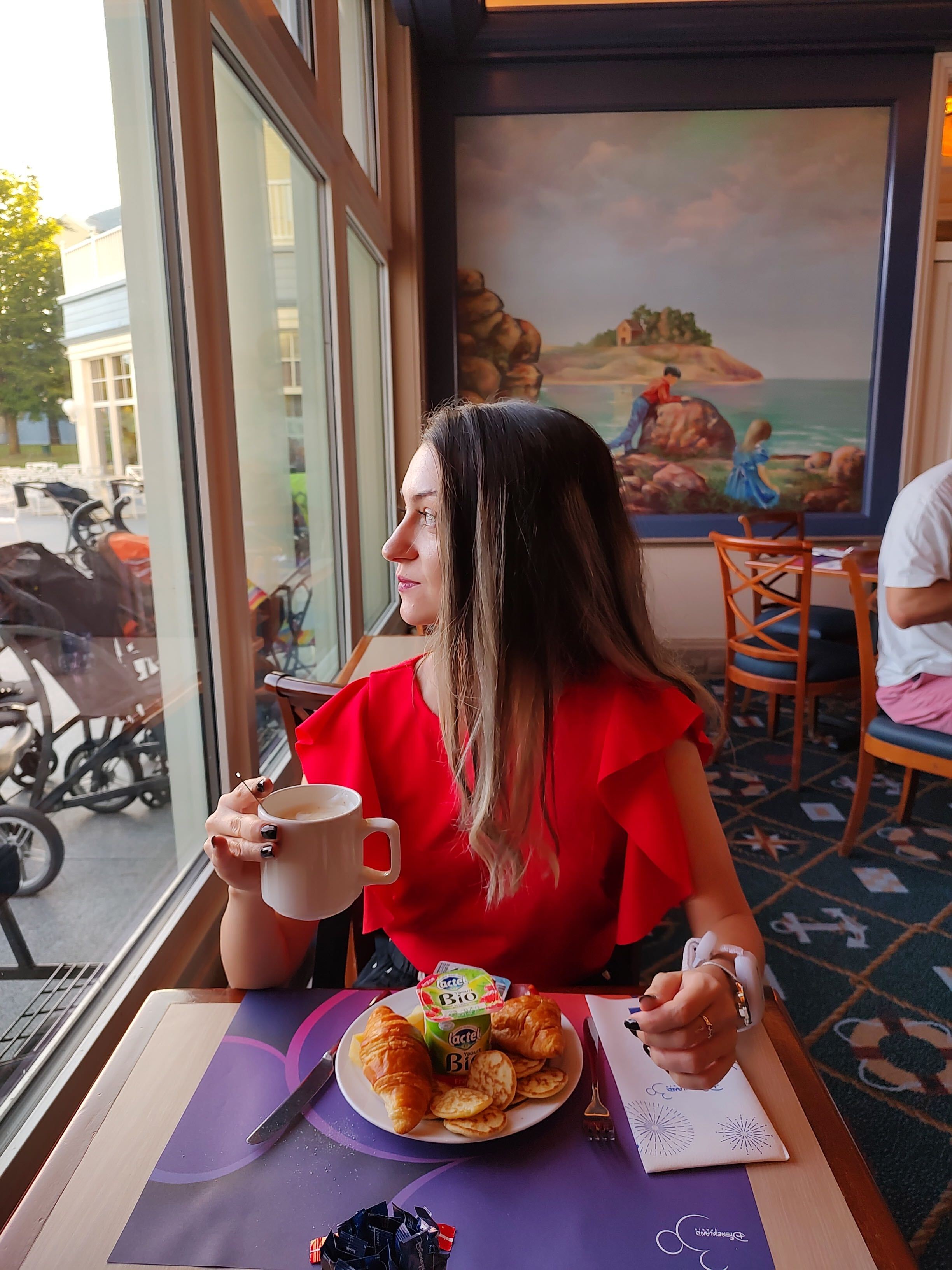 A girl visiting Disneyland, having a meal and looking through a window