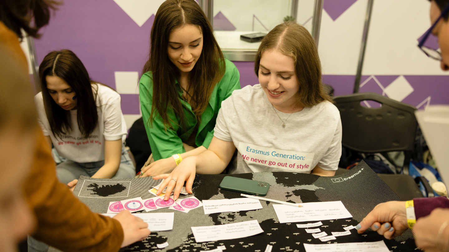 A picture of people at a stand looking at stickers and other materials.