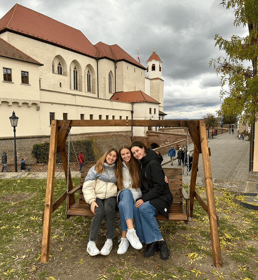 PHOTO 3: Saulė, with two friends, on a wooden swing