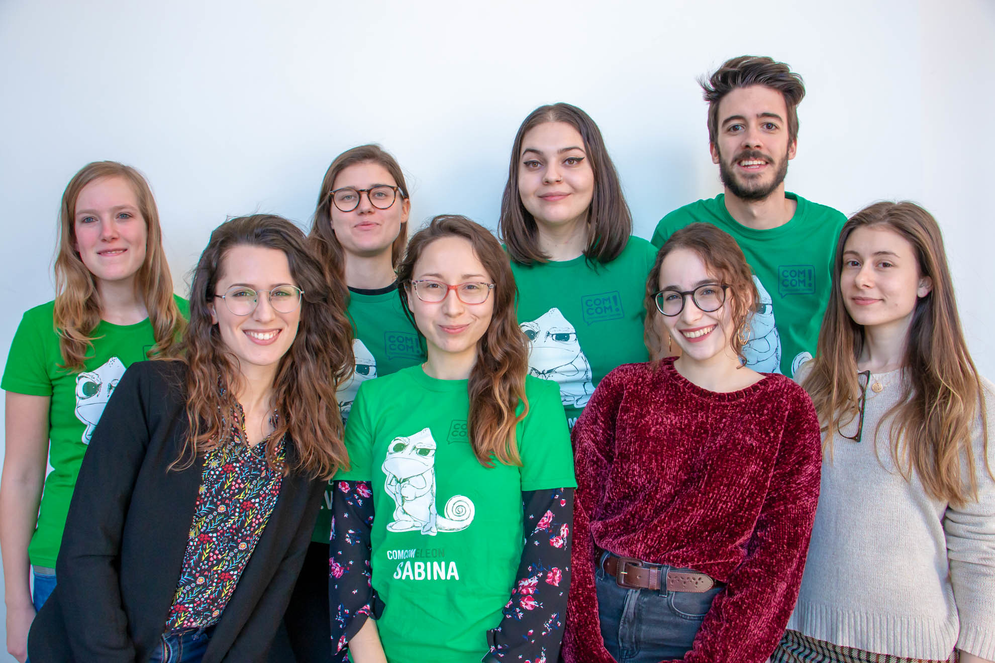 Eight people posing for a group picture in green T-shirts