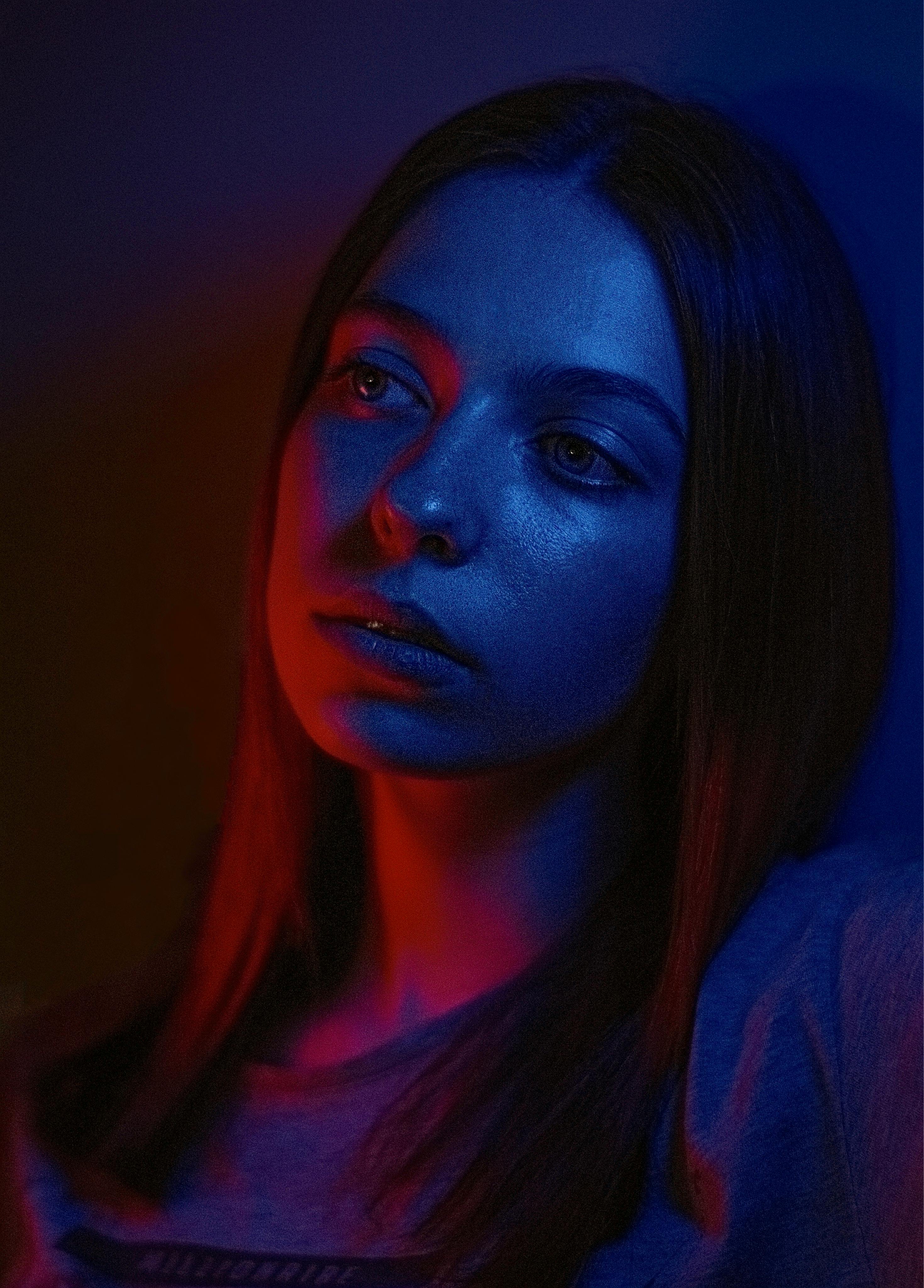 A close-up-shot of a woman in a dark-purple and red light