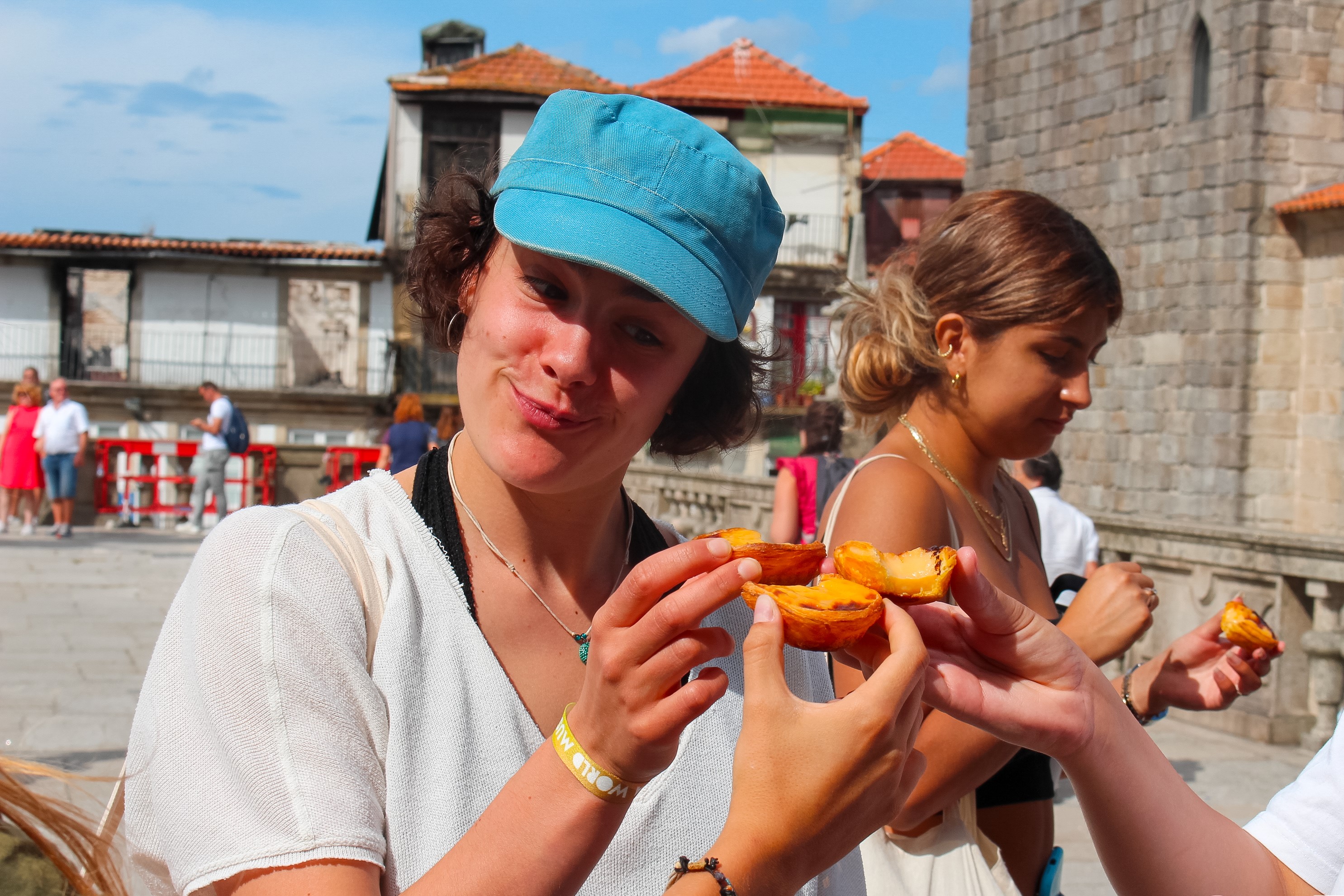 A person holding a Pastel de Nata together with two other people.