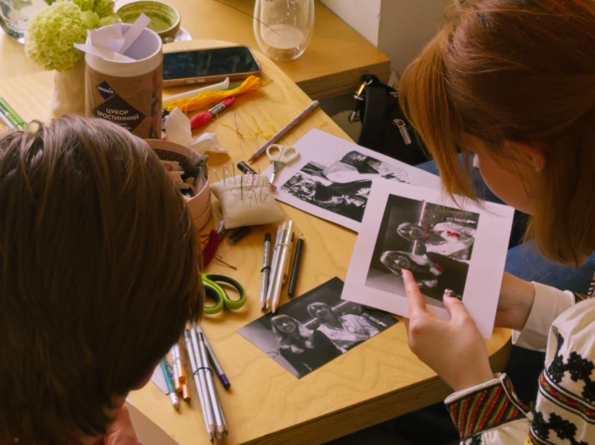 The image shows two people holding pictures in white and black