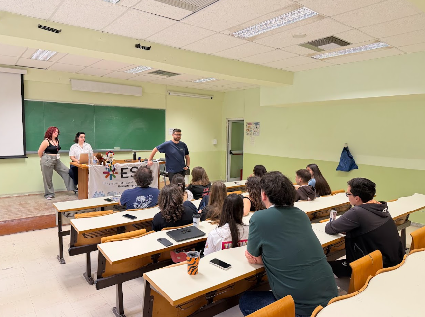 The image shows a group of young people in a classroom attending other people presenting