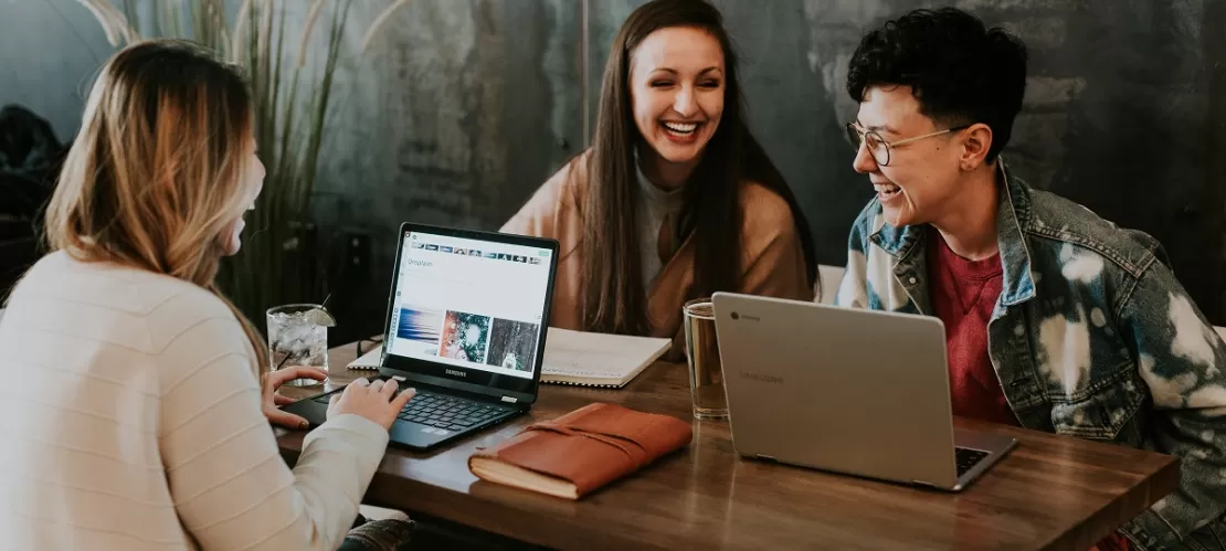 three people sitting in front of table laughing together