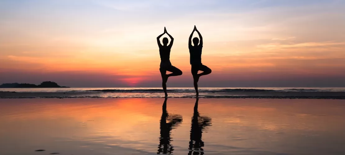 two persones doing yoga in front of the sea