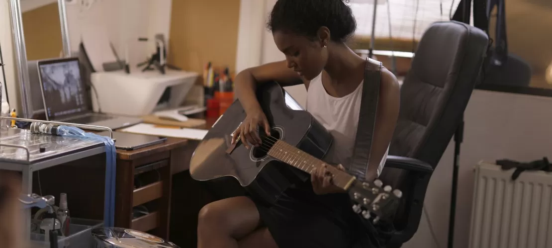 woman in white top playing acoustic guitar