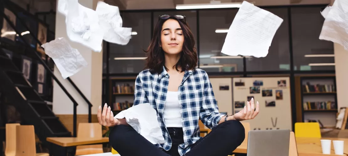 woman sit on desk with flying papers around