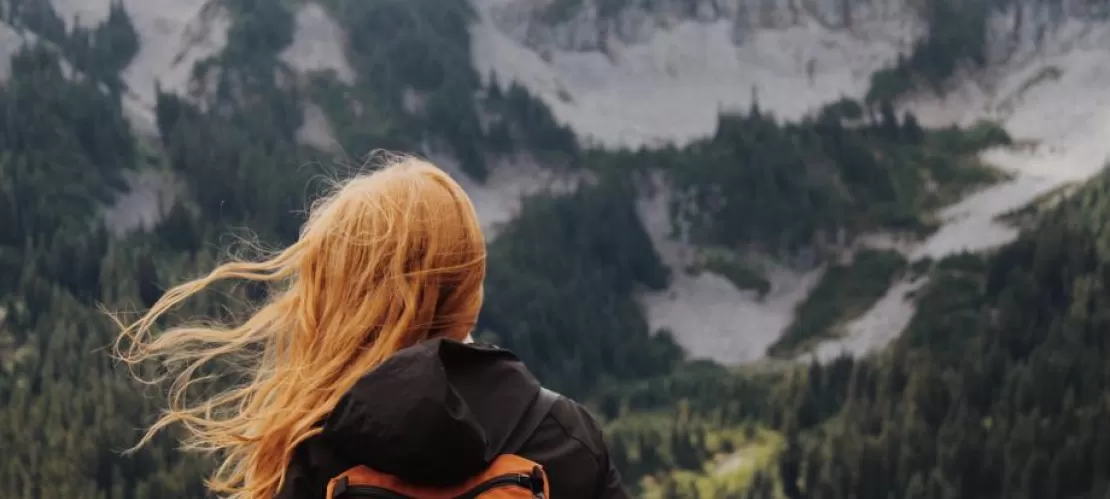 woman with bagpack looking at nature, from back