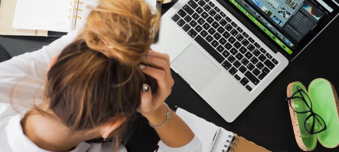 someone with head in hands looking at laptop, view from above