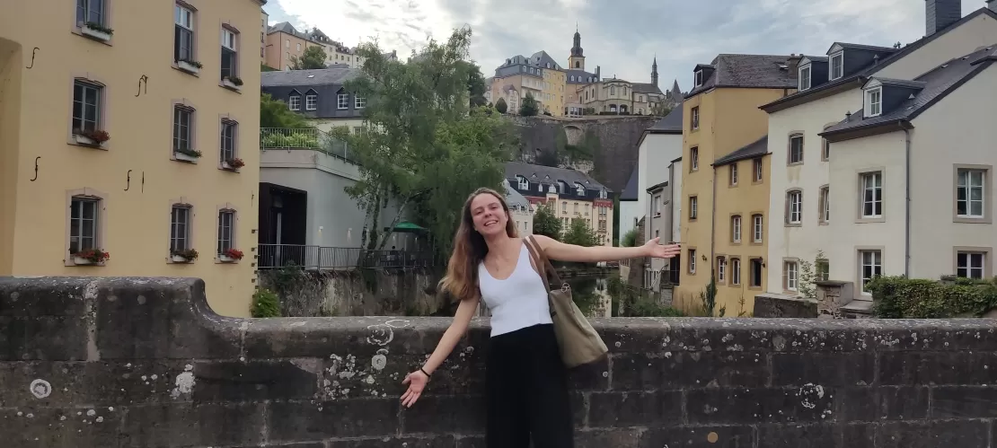 A girl posing to the camera, with buildings behind her