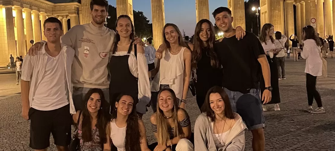 A group of international students standing in front of Brandenburger Tor in Berlin, taking a photo in the evening hours