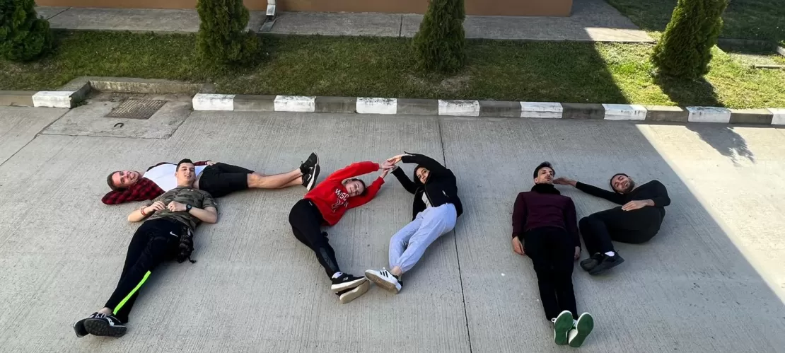 Six Participants of the youth exchange project lying down on the ground and creating letters with their bodies.